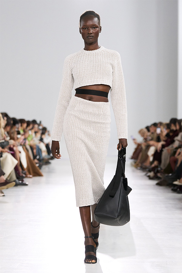 Max-Mara-Show Frühjahr/Sommer 2026 – Weißer Look mit Cropped-Pullover zu einem Midirock und einer schwarzen Tasche.