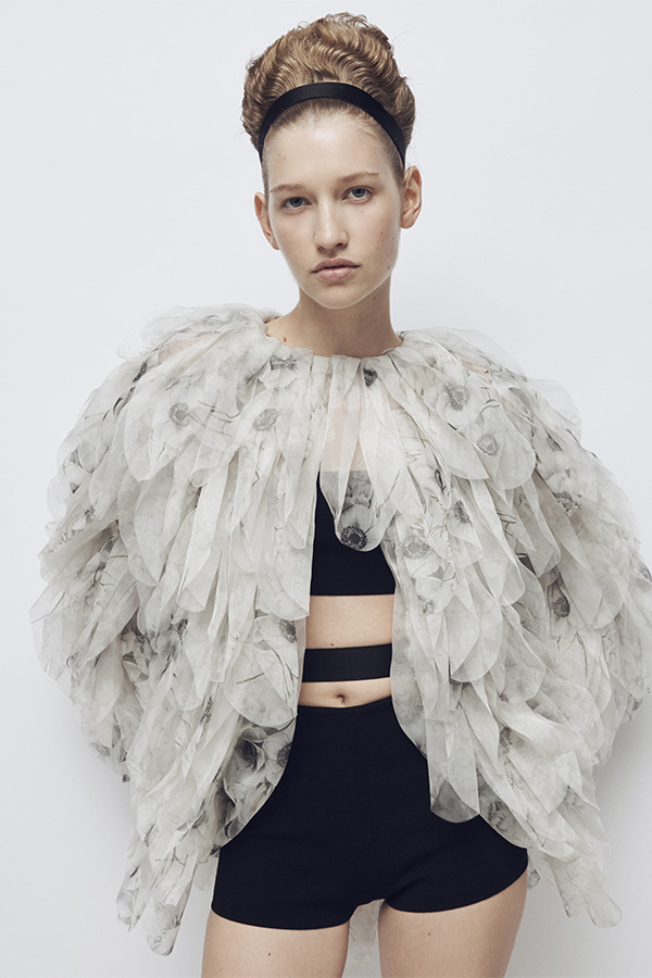 Max-Mara-Show Frühjahr/Sommer 2026 – Model mit Look mit weißer Jacke mit Details, Bandeau-Top und schwarzer Shorts.