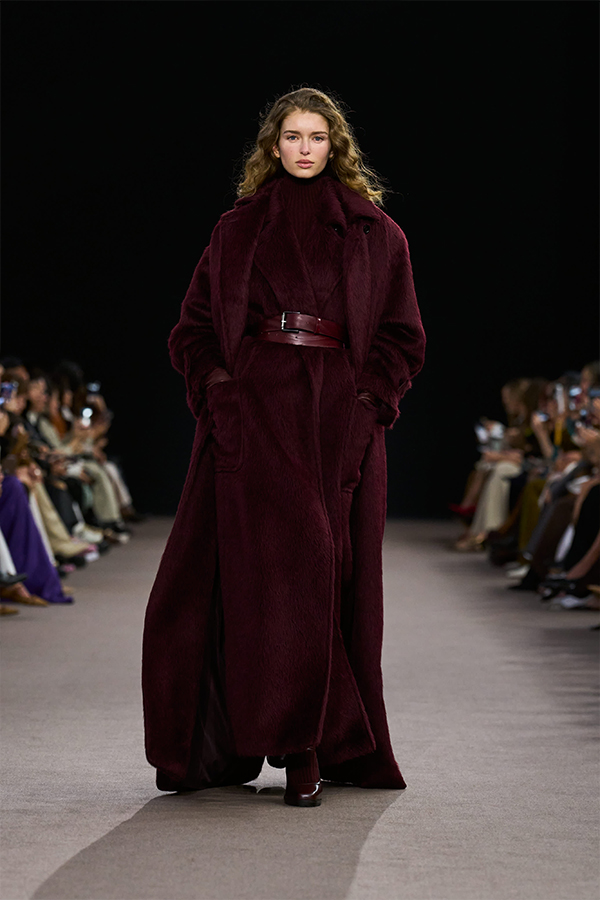 Max-Mara-Show Herbst/Winter 2025 – Look in Kirschrot mit langem Mantel, ärmellosem Mantel, Gürtel, Leggings und Mary Janes.